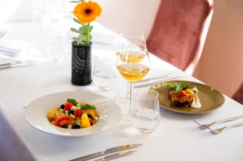 a table with two plates of food and a glass of wine at Moulin de Vernègues Hôtel & Spa in Mallemort
