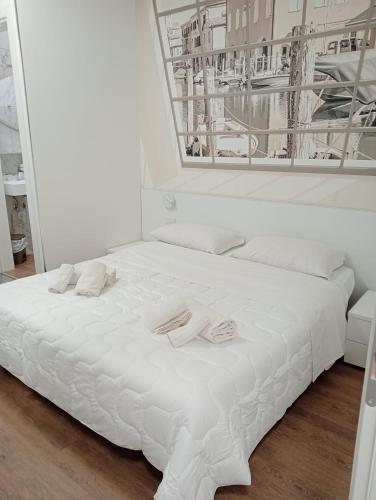 a white bed with two slippers on top of it at Hotel Ragno D'Oro in Sottomarina