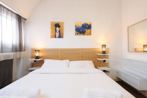 Un dormitorio con una cama blanca y dos cuadros en la pared. en Primopiano - Fargorida 6, en Milán