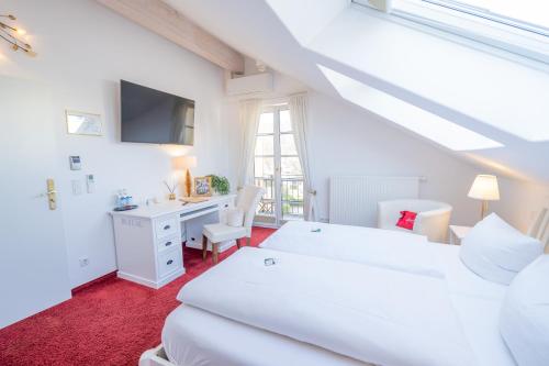 a white bedroom with a desk and a bed at Landhaus Hotel Wolfratshausen in Wolfratshausen