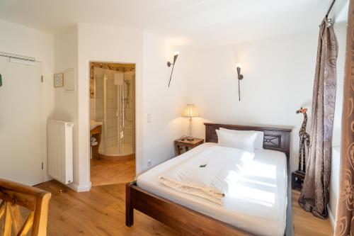 a bedroom with a large white bed and a bathroom at Landhaus Hotel Wolfratshausen in Wolfratshausen