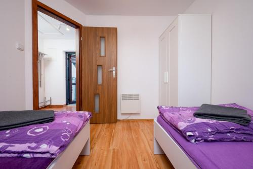 2 łóżka w pokoju z fioletową pościelą w obiekcie Apartamenty Plazowa w Darłówku