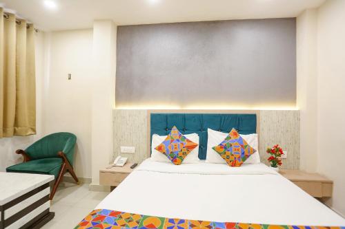 FabHotel Hari Kunj في فاراناسي: غرفة نوم بسرير كبير وكرسي