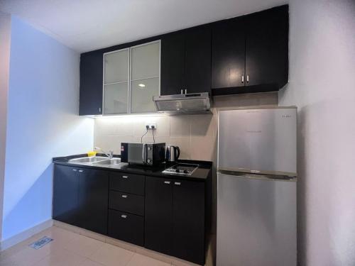a kitchen with black cabinets and a stainless steel refrigerator at Vacation Stay at Resort Suites Bandar Sunway in Kampong Penaga