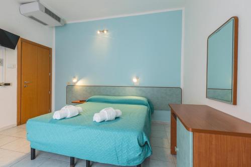 a bedroom with a bed with two towels on it at Hotel La Perla in Cervia