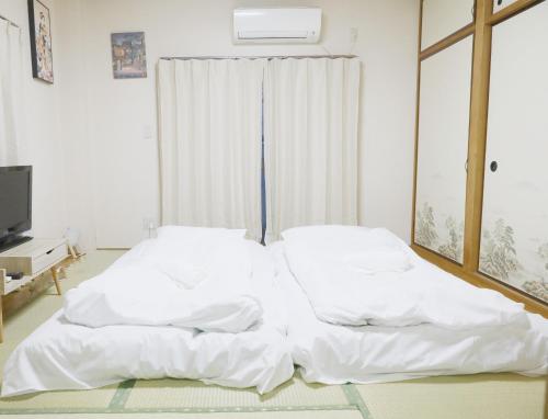 2 białe łóżka w pokoju z oknem w obiekcie TOKYOSTYLE w Tokio