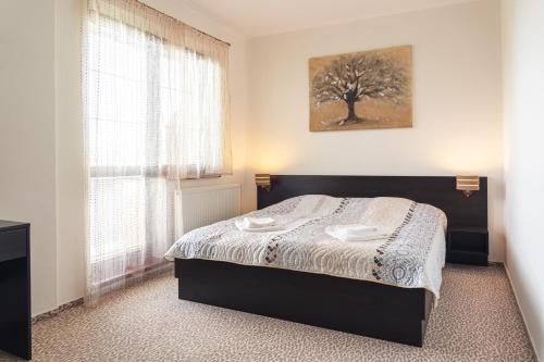 a bedroom with a bed and a window with a tree at TATRYSTAY Apartments Tatranska in Veľká Lomnica
