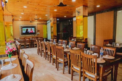 a restaurant with wooden tables and chairs and a tv at Hotel natraj pachmarhi in Pachmarhī