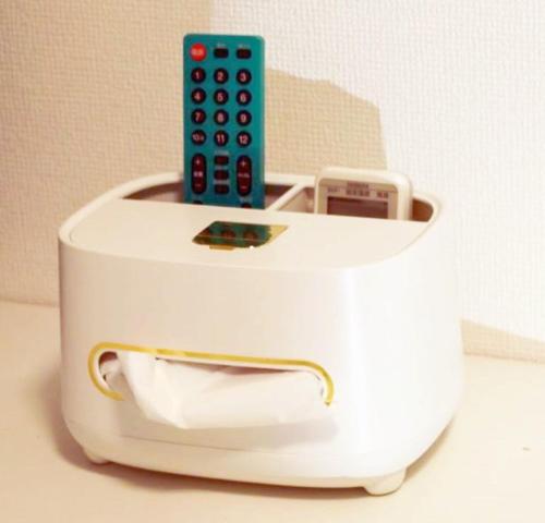 a white toaster with a cell phone and a remote control at TOKYOSTYLE in Tokyo
