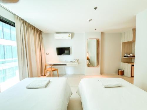 a hotel room with two beds and a desk at Zand Morada Pattaya in Jomtien Beach