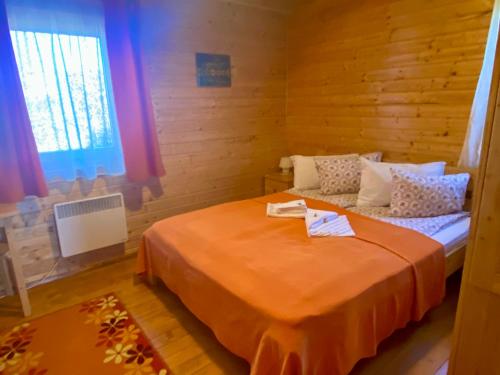 sypialnia z łóżkiem z pomarańczowym kocem w obiekcie Nimfa Apartments w mieście Păuleni-Ciuc