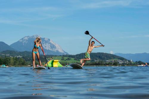 two people on paddle boards in the water at nawu apartments & Restaurant in Hermagor