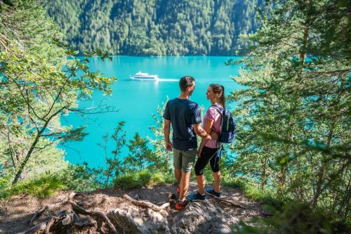 two people standing on a trail looking at a lake at nawu apartments & Restaurant in Hermagor