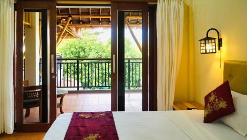 a bedroom with a bed and a view of a balcony at Vamana Bangsal in Pawenang