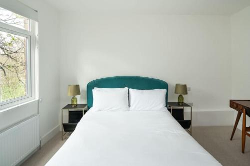a white bed with a green headboard in a bedroom at 1 Bedroom flat in Barons Court in London
