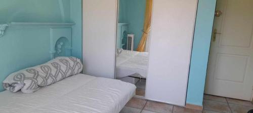 Cette chambre comprend un lit blanc et un miroir. dans l'établissement Chambre privée et climatisée dans un appartement de 4 chambres, à Toulon