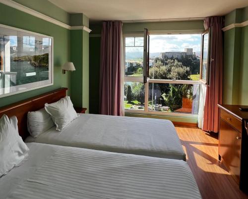 a bedroom with two beds and a large window at Hotel Faro de San Vicente in San Vicente de la Barquera