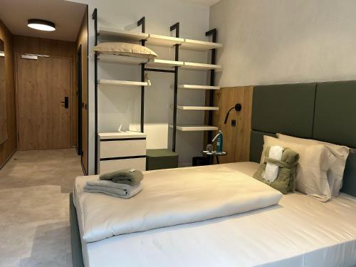a bedroom with a large white bed and shelves at DAS ERZ Medical Spa & Hotel in Crottendorf