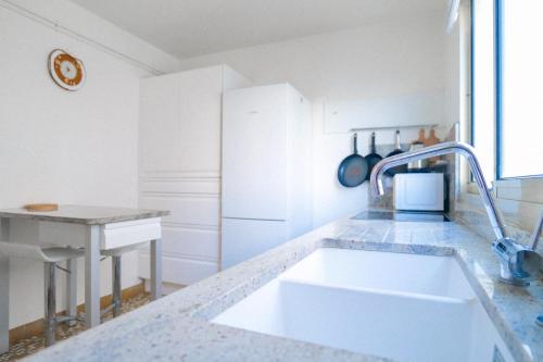 une cuisine blanche avec un évier et un comptoir dans l'établissement Appartement vue baie des Sables d Olonne 5 personnes, à Les Sables-dʼOlonne
