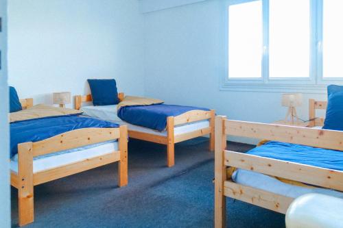 Cette chambre comprend 3 lits superposés avec des draps bleus. dans l'établissement Appartement vue baie des Sables d Olonne 5 personnes, à Les Sables-dʼOlonne