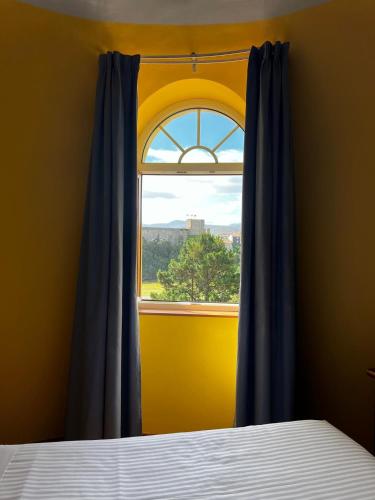 a bedroom with a window with blue curtains and a bed at Hotel Faro de San Vicente in San Vicente de la Barquera