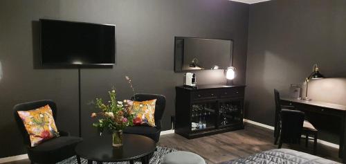 uma sala de estar com uma televisão e uma mesa e cadeiras em Hotell Iföhus em Bromölla
