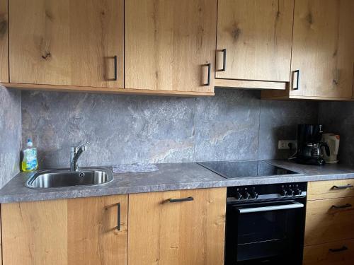 a kitchen with a sink and a stove and wooden cabinets at Mönchsberghof in Kleinarl