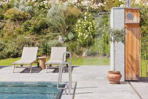 two white chairs sitting next to a swimming pool at Hotel Weissenstein in Sankt Michael im Lungau