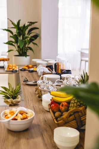 a wooden table topped with bowls of fruits and vegetables at Hotel La Perla in Cervia