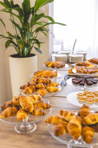 a table topped with plates of pastries and pies at Hotel La Perla in Cervia