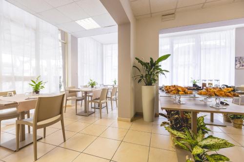 a dining room with tables and chairs and windows at Hotel La Perla in Cervia