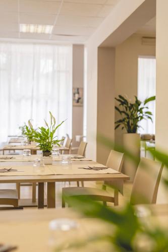 a dining room with tables and chairs and plants at Hotel La Perla in Cervia