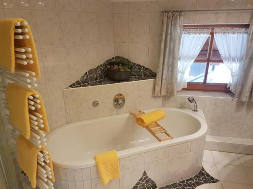 baño con bañera blanca y ventana en Zum Eichhof, en Reit im Winkl