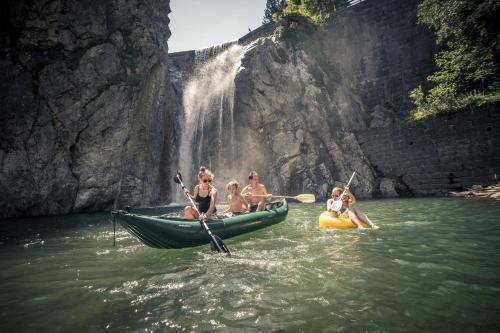 a group of people in a canoe in front of a waterfall at nawu apartments & Restaurant in Hermagor
