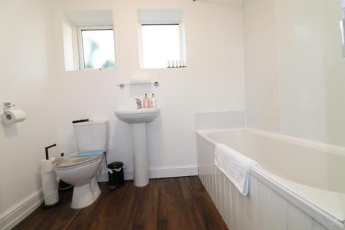 La salle de bains blanche est pourvue de toilettes, d'une baignoire et d'un lavabo. dans l'établissement Central Modern House, Greenhithe, à Kent
