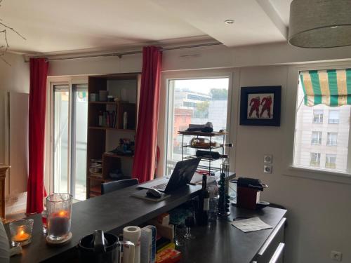 une cuisine avec un bureau et une fenêtre avec des rideaux rouges dans l'établissement Spécial jeux olympiques, à Levallois-Perret