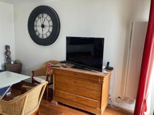 - une télévision au-dessus d'une commode avec une horloge sur le mur dans l'établissement Spécial jeux olympiques, à Levallois-Perret