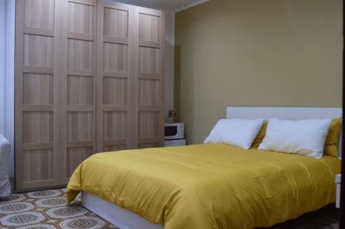 een slaapkamer met een groot bed en een gele deken bij La Perla in Isola delle Femmine