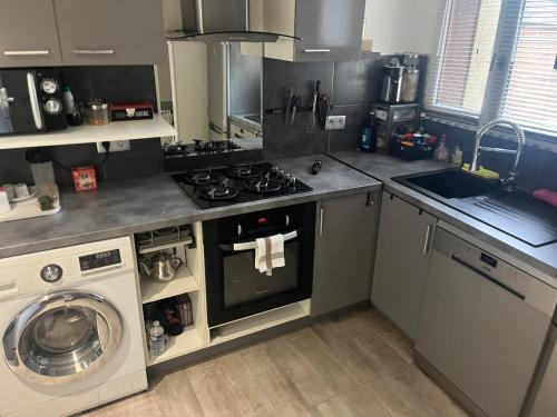 une cuisine avec une cuisinière et une machine à laver dans l'établissement Chambre à louer dans maison de ville cosy proche rer A, à Limeil-Brévannes