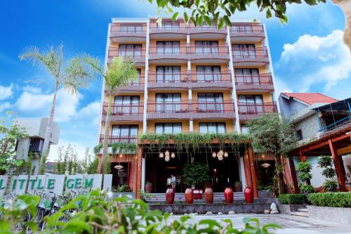 een hoog roze gebouw met bomen ervoor bij Little Gem. An Eco-Friendly Boutique Hotel & Spa in Hội An