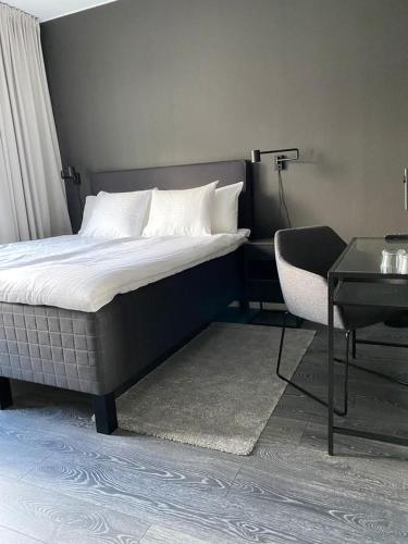 a bedroom with a bed and a chair and a table at Hotell Iföhus in Bromölla