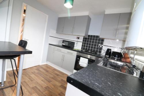 a kitchen with white cabinets and a black counter top at Central Modern House, Greenhithe in Kent