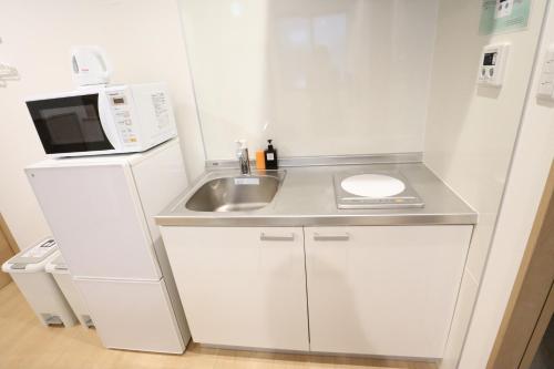 a small white kitchen with a sink and a microwave at KYOSTAY Iroha Komichi in Kyoto