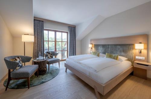 a bedroom with a large white bed and a chair at Hotel Gasthof Kammbräu in Zenting