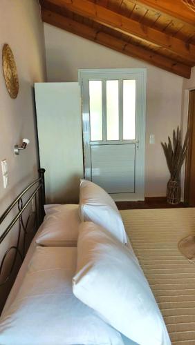 a bedroom with a bed with white pillows and a door at Elena's Seafront Deluxe Studios in Zakynthos