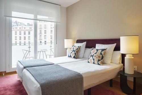 1 Schlafzimmer mit einem Bett mit 2 Lampen und einem Balkon in der Unterkunft Muinoa 2 by FeelFree Rentals in San Sebastián
