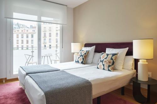 une chambre avec un lit avec deux lampes et un balcon dans l'établissement Muinoa 2 by FeelFree Rentals, à Saint-Sébastien