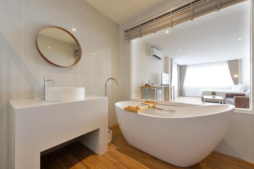 a white bathroom with a tub and a sink at Ratchathewi Hyde Away in Pratunam