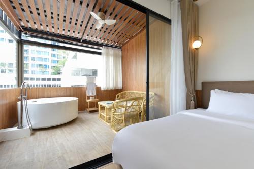 a bedroom with a bed and a bathtub and a bed and a bed at Ratchathewi Hyde Away in Pratunam