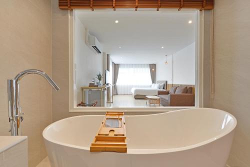 a bath tub in a bathroom with a living room at Ratchathewi Hyde Away in Pratunam
